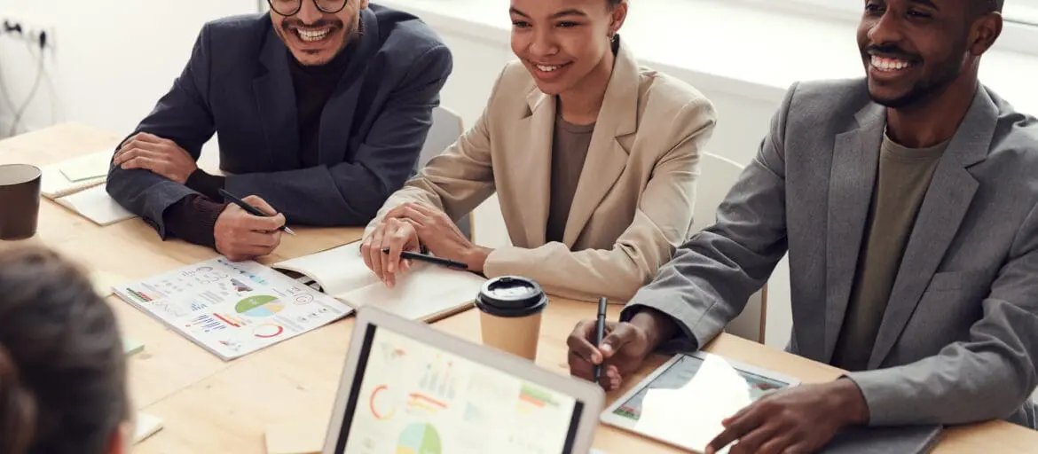 Group of three employees on a meeting table smiling